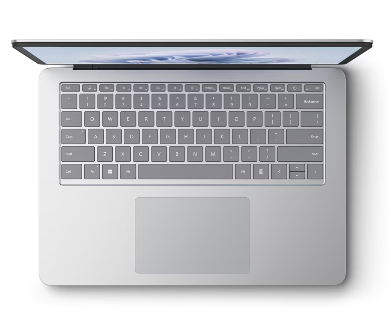 Vista cenital de un portátil sobre una superficie blanca. La pantalla está abierta, el teclado visible y el panel táctil debajo.