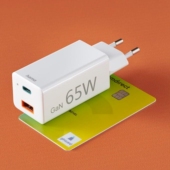 Cargador blanco Hama GaN 65W en una tarjeta de crédito amarilla. Fondo naranja.