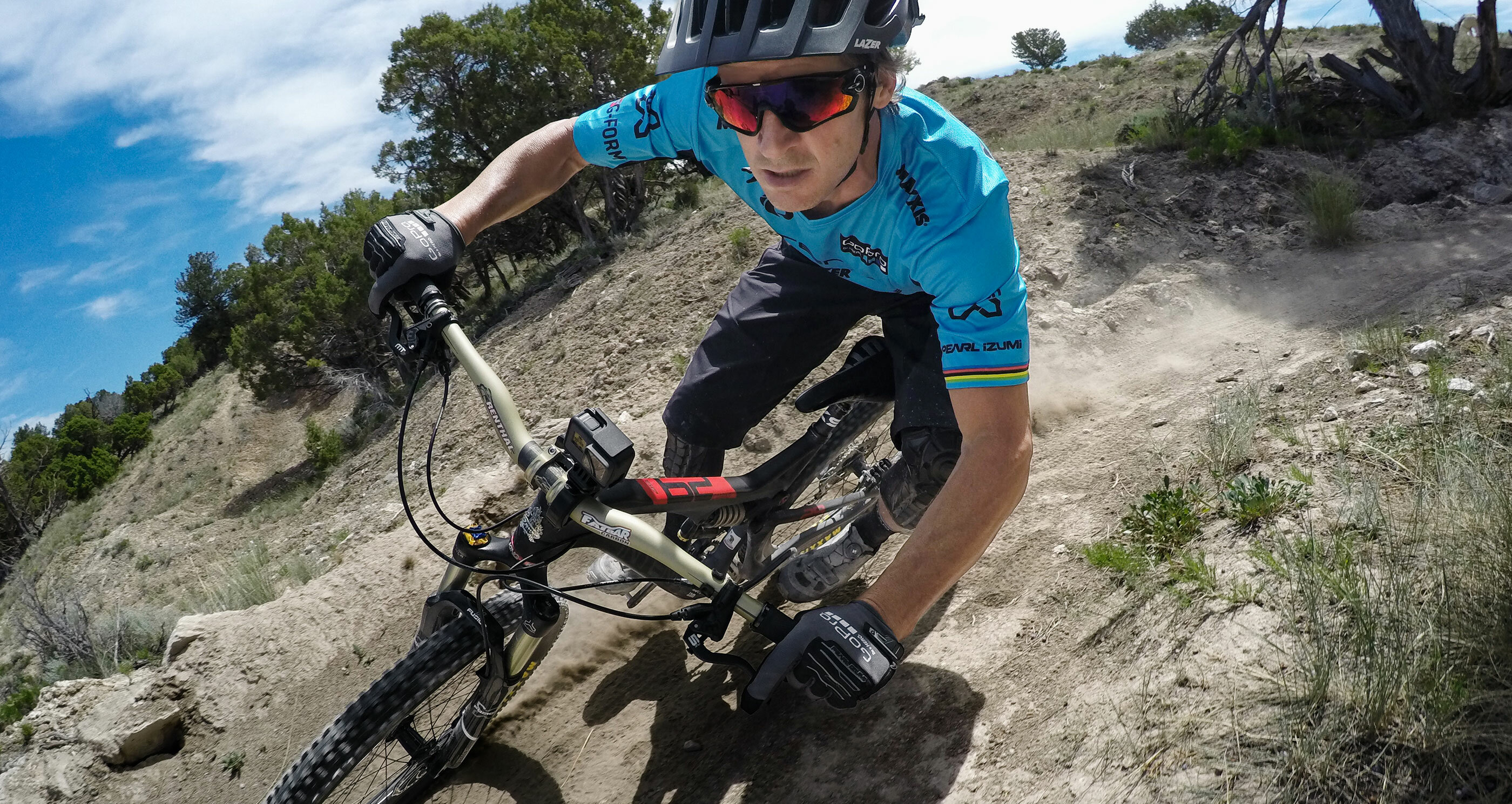 Mężczyzna w okularach przeciwsłonecznych jadący na rowerze górskim po polnej ścieżce.