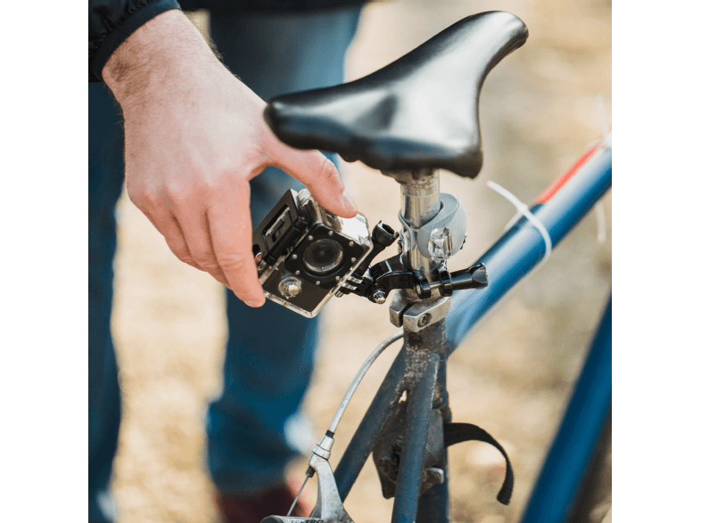 Osoba montująca kamerę GoPro na sztycy siodełka roweru.