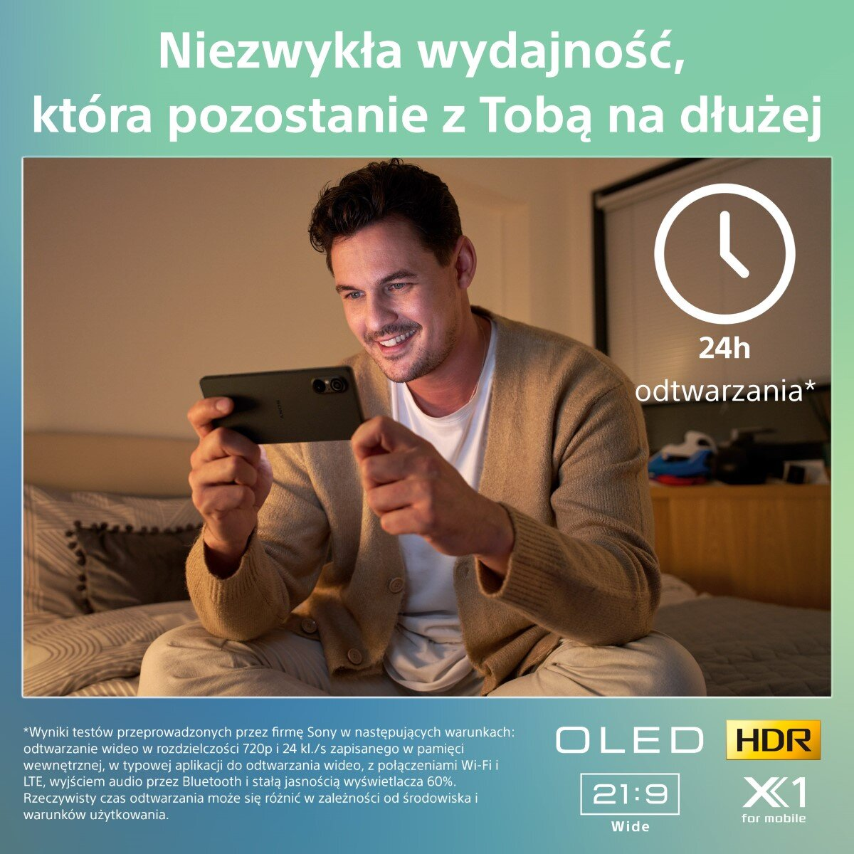 Mężczyzna uśmiecha się trzymając telefon. Tekst po polsku: 'Niezwykła wydajność... 24h odtwarzania'.