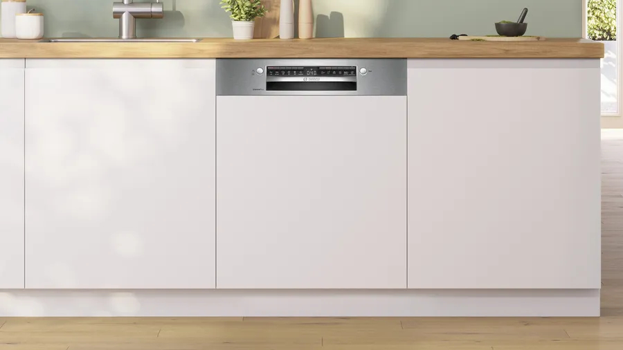 Moderner Geschirrspüler in weißen Schränken eingebaut. Zeigt einen digitalen Bildschirm und Tasten. Holz-Arbeitsplatte oben.