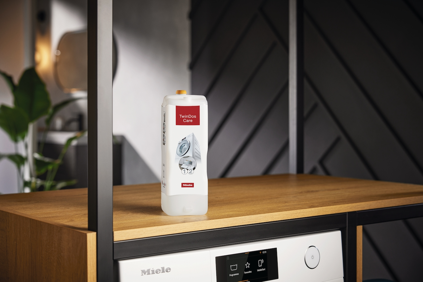 Eine Flasche Miele TwinDos Care Waschmittel auf einem Holzregal im Waschraum.