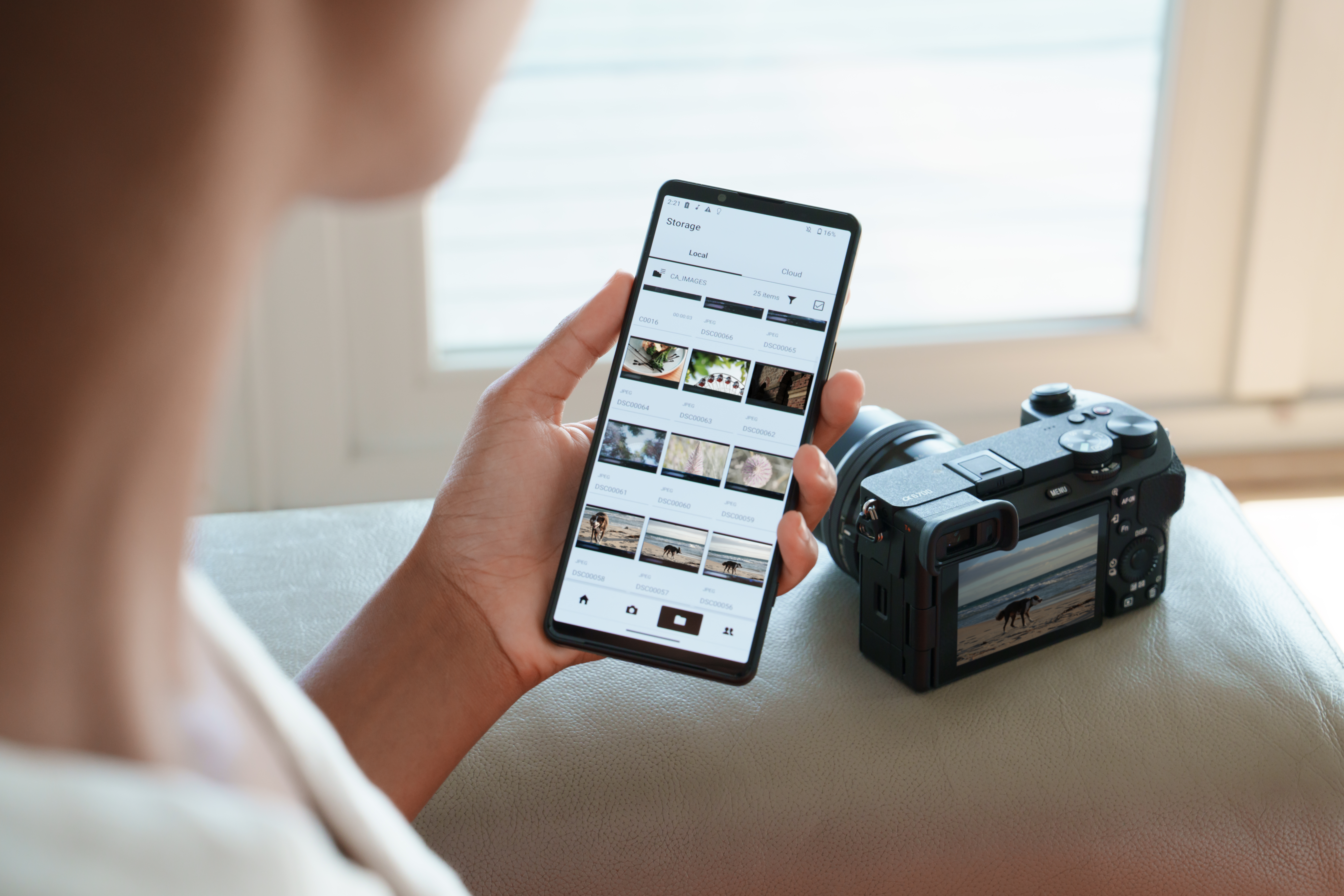 Persona che tiene un telefono che mostra foto, fotocamera nelle vicinanze.