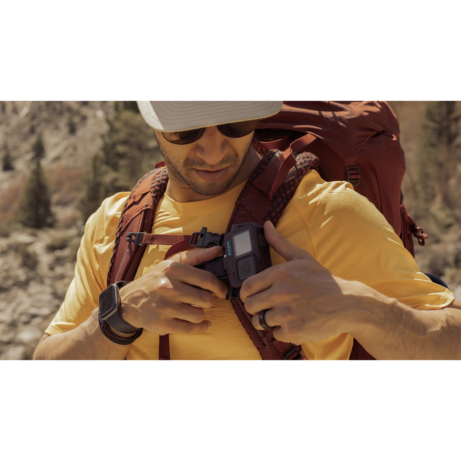 Uomo con GoPro sul petto, con zaino e occhiali da sole.