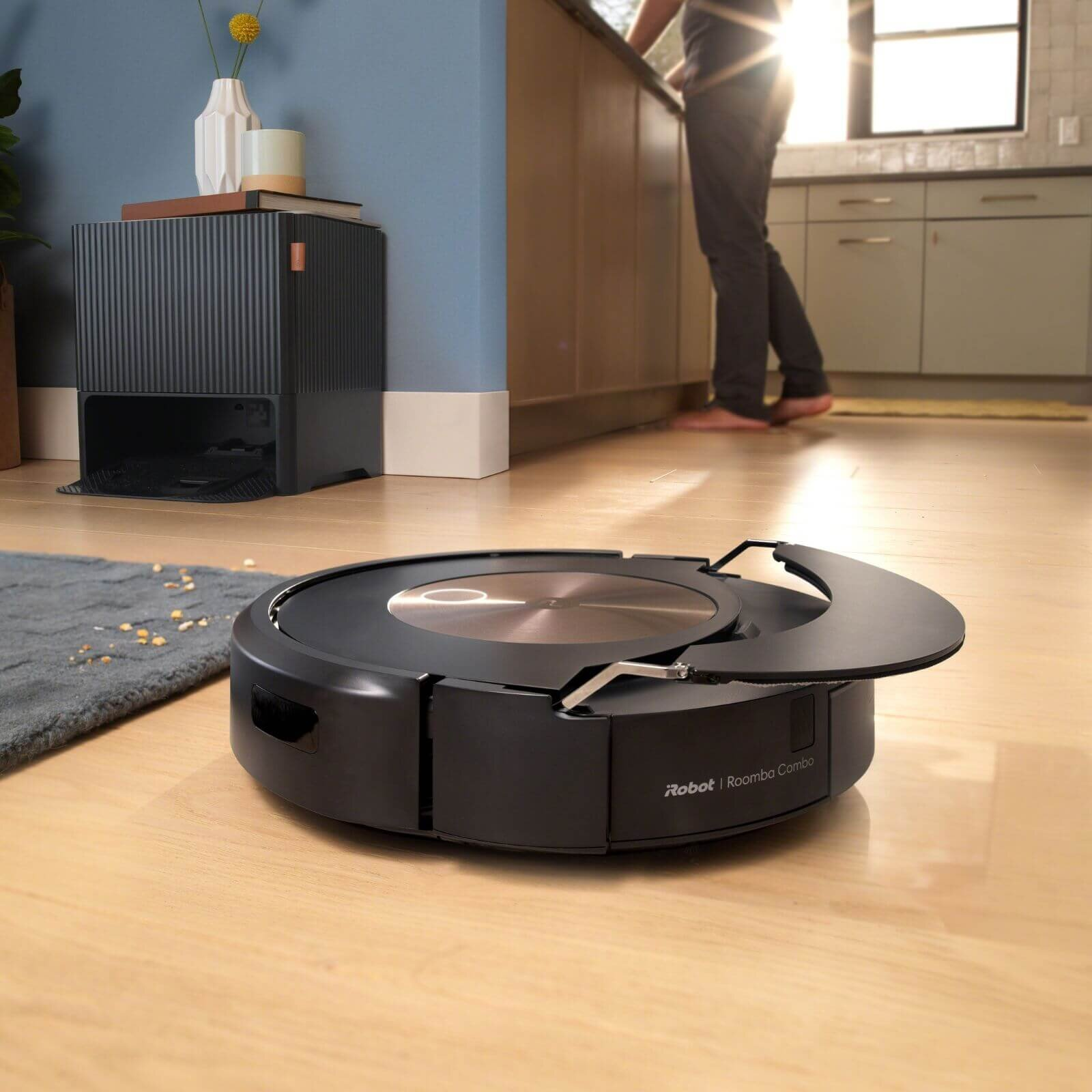 Czarny odkurzacz automatyczny Roomba na drewnianej podłodze w kuchni.