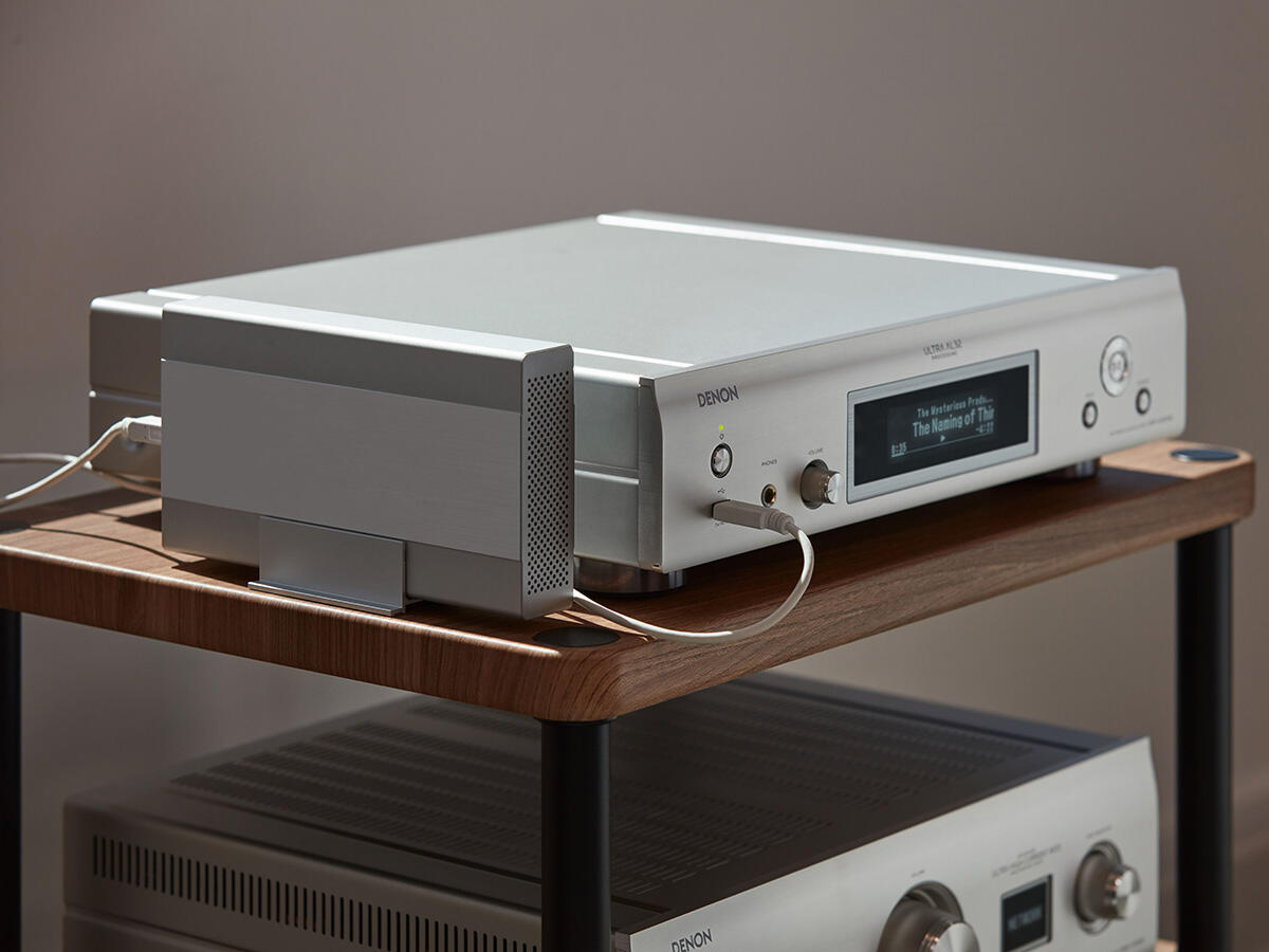 Silbernes Audiokomponenten-System auf Holzregal. Ein Denon-Audiosystem.