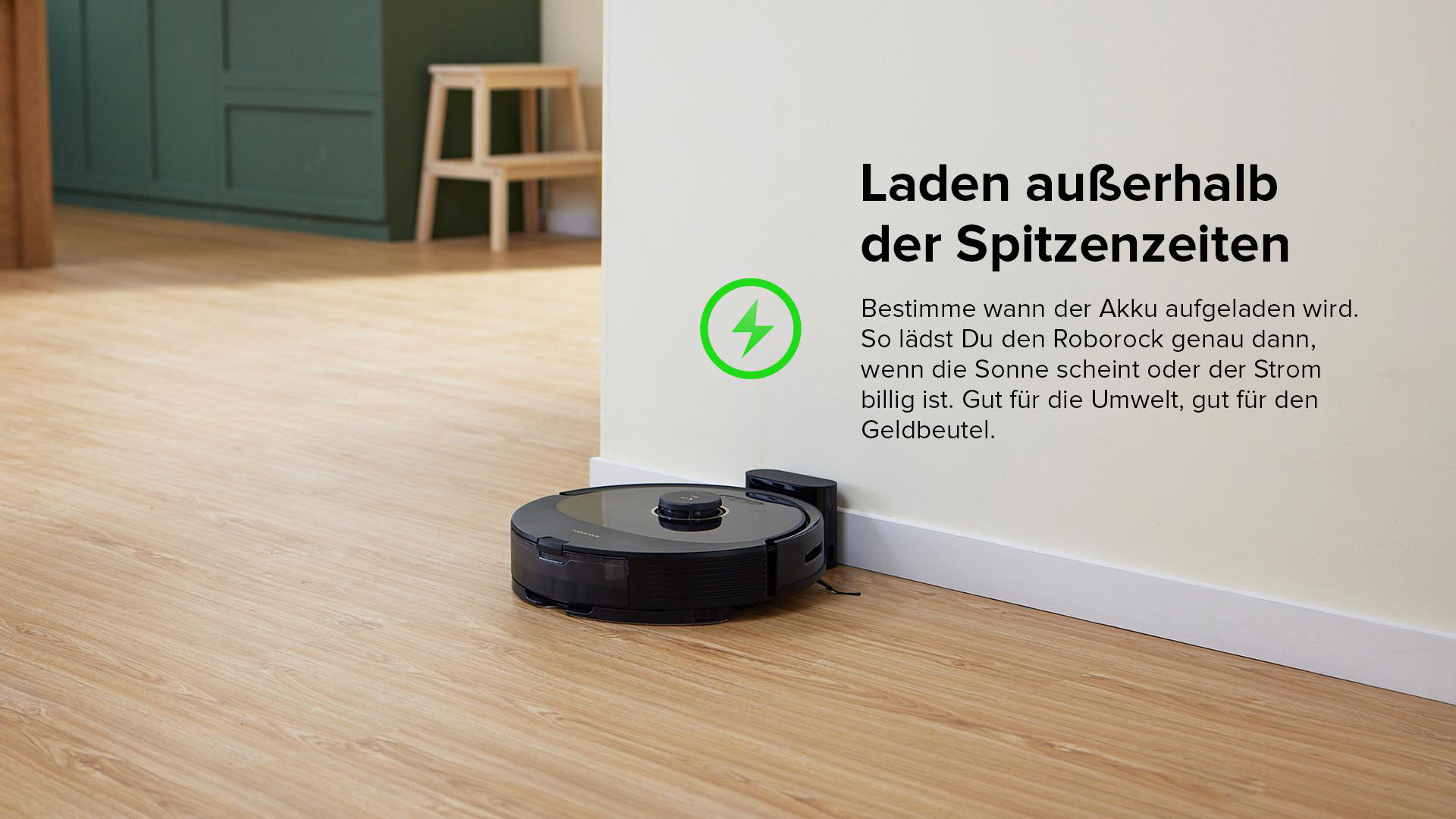 Ein schwarzer Roboter-Staubsauger auf einem Holzboden neben einer Wand.