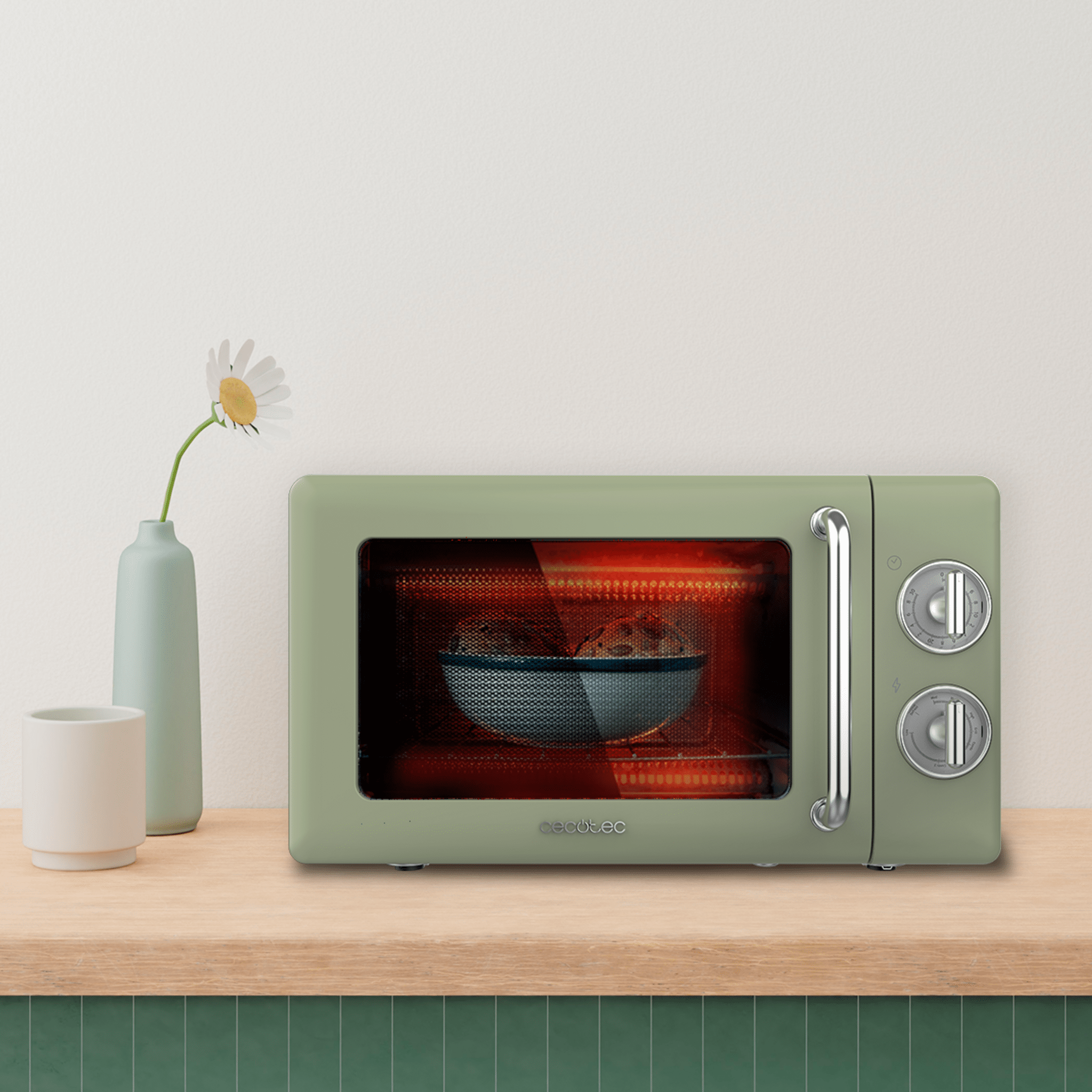 Un horno microondas verde sobre una mesa de madera con un jarrón.