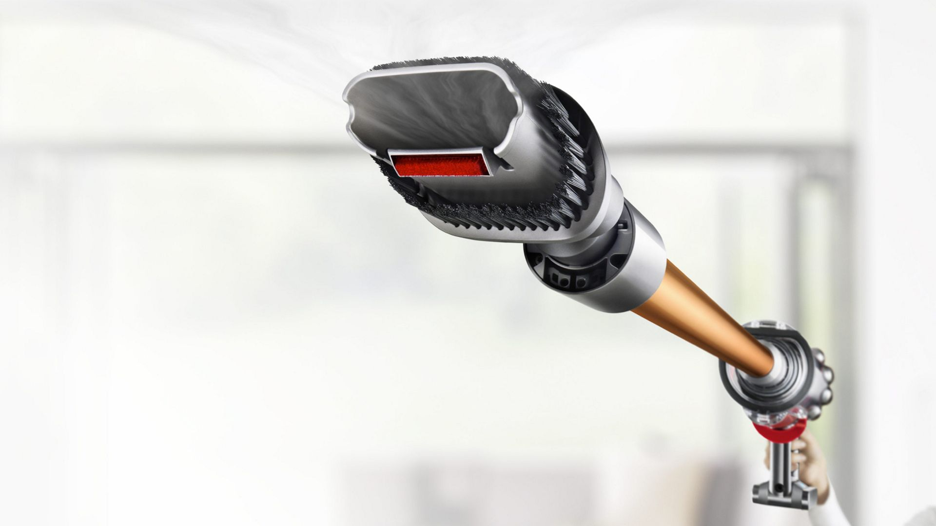 Gümüş kafalı ve turuncu borulu el tipi bir elektrikli süpürge. Baştan buhar çıkıyor.