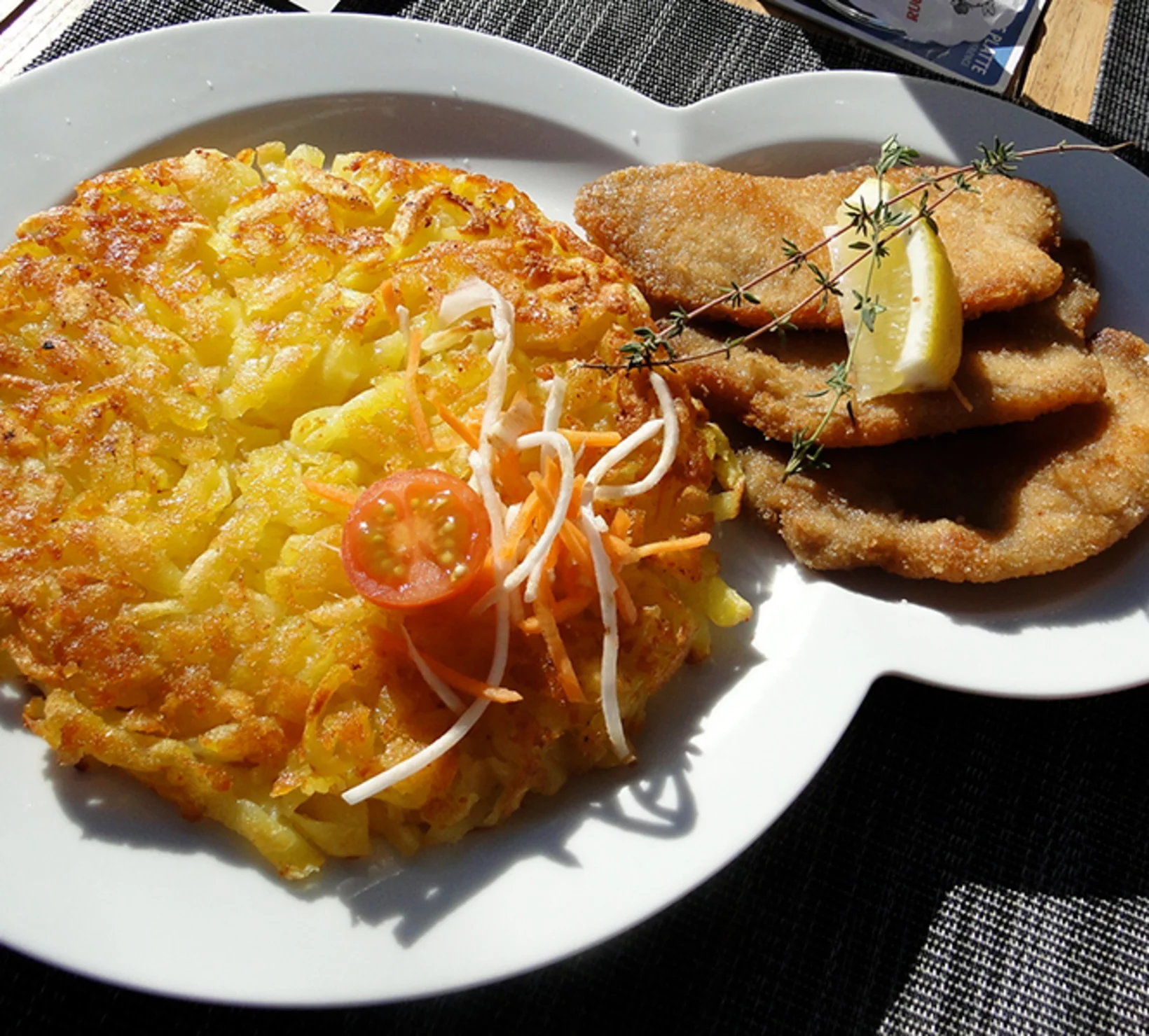 Un piatto di frittelle di patate fritte e carne con una fetta di limone.