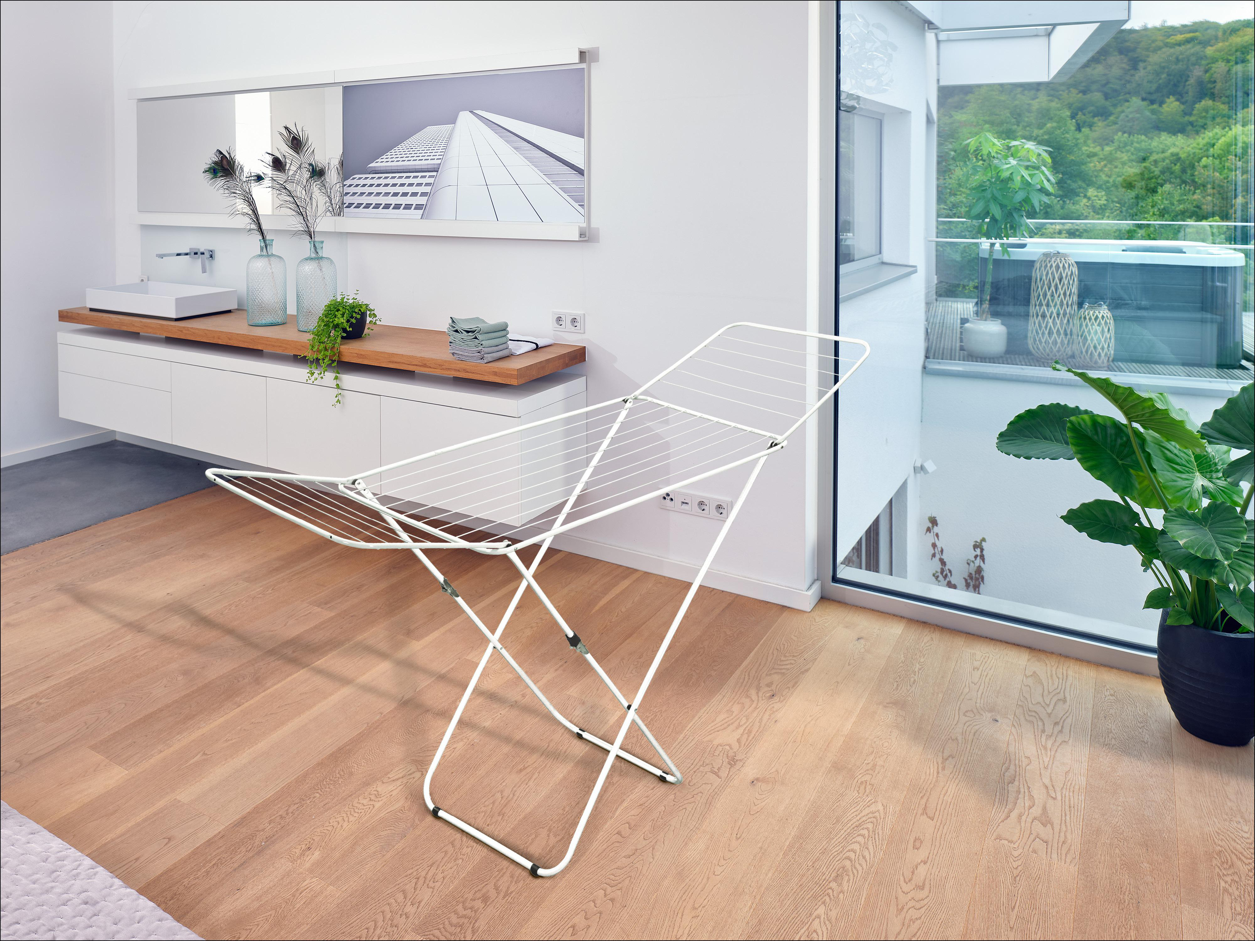 Weißer Wäscheständer in einem Raum mit Holzböden und einem großen Fenster.