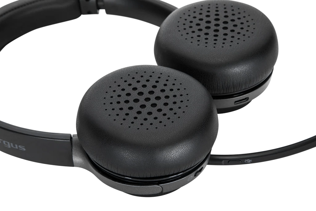 Un par de auriculares negros. Las almohadillas son redondas y tienen agujeros. El fondo es blanco.