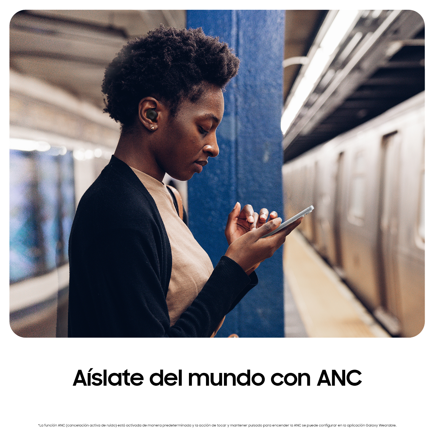 Mujer en estación de metro usando teléfono con auriculares. Texto 'Aíslate del mundo con ANC' debajo.