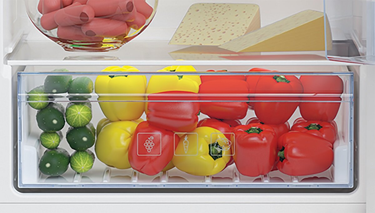 Szuflada na warzywa wypełniona papryką, ogórkami i pomidorami.