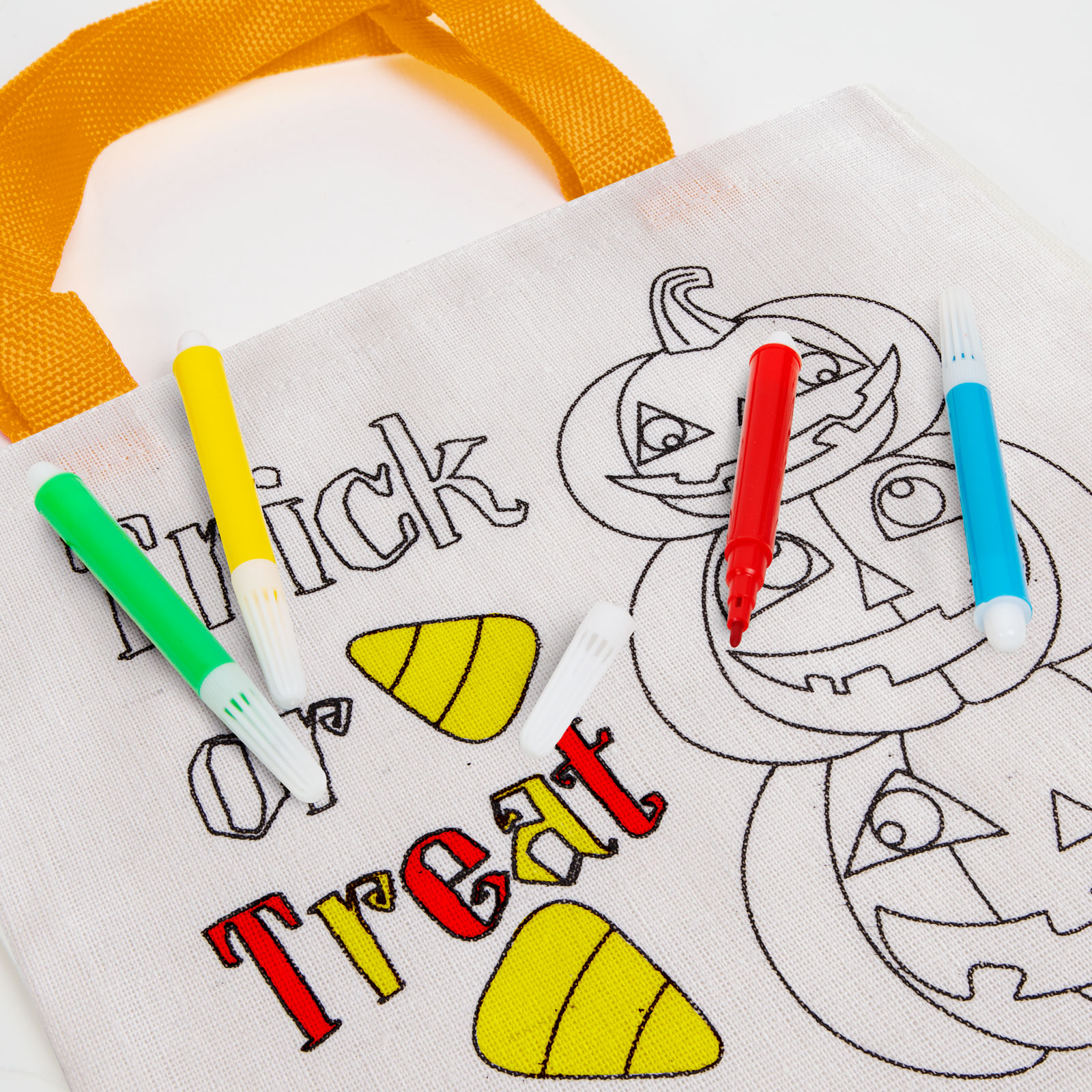 Fehér Halloween-zsák színes markerekkel és Halloween témájú rajzokkal.