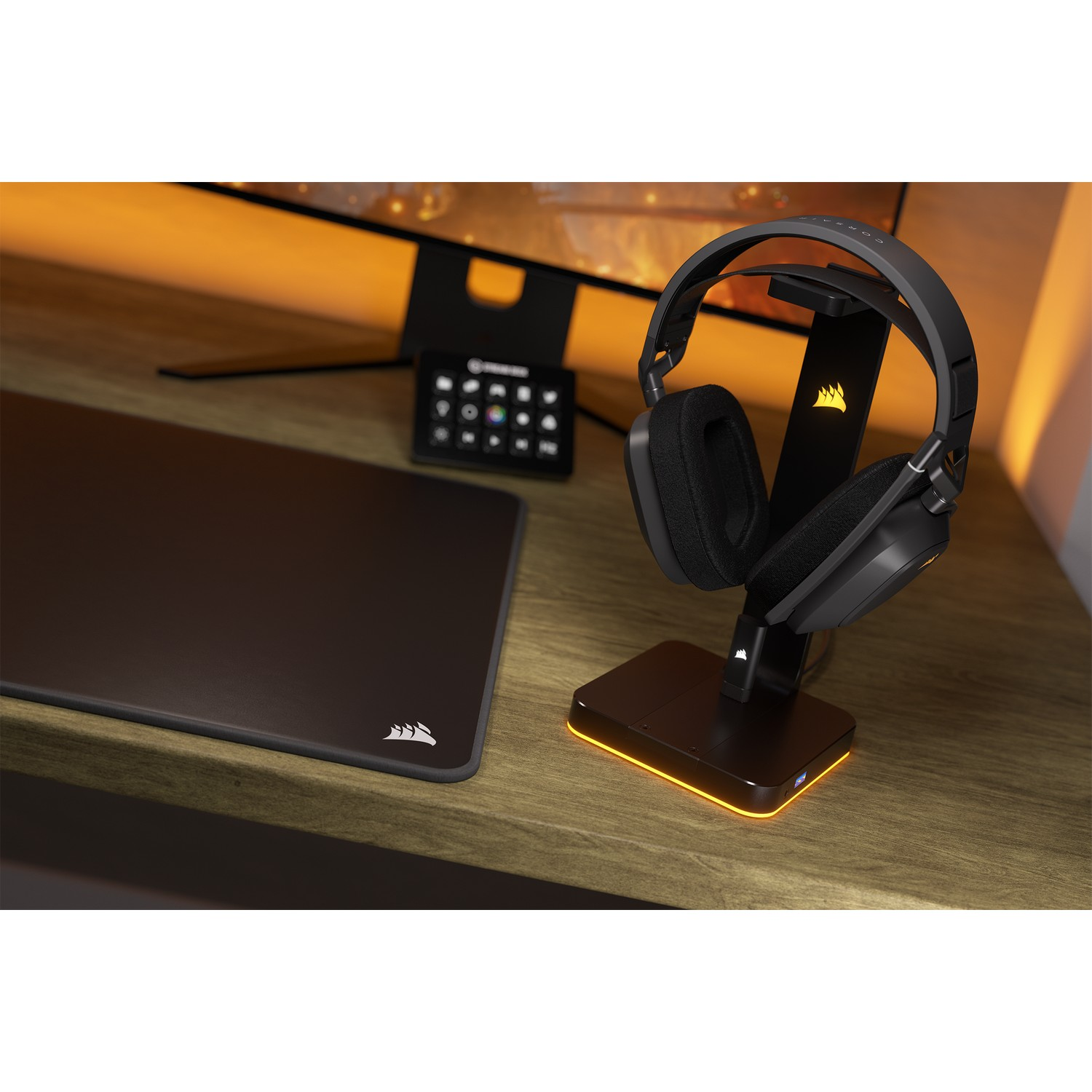 Casque sur support, souris et tapis sur bureau en bois. Moniteur en arrière-plan.