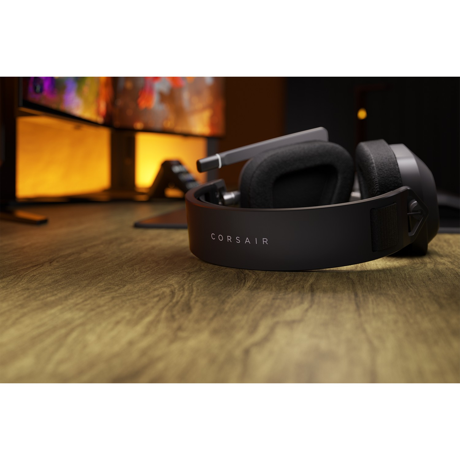 Casque Corsair noir sur une table en bois, avec un écran en arrière-plan.