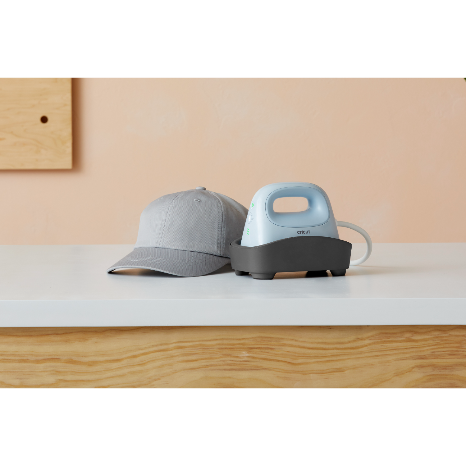 A gray hat and a light blue heat press with a black stand are on a white table.