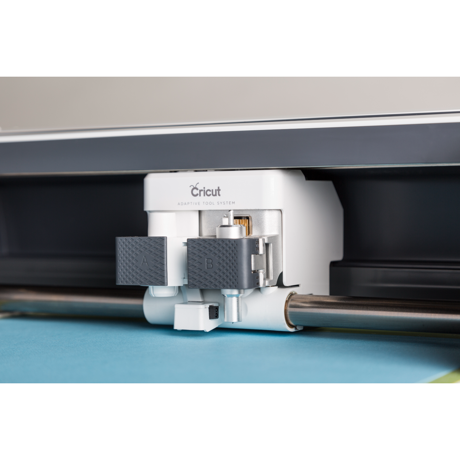 Close-up of a Cricut machine cutting tool. The machine is white and gray.
