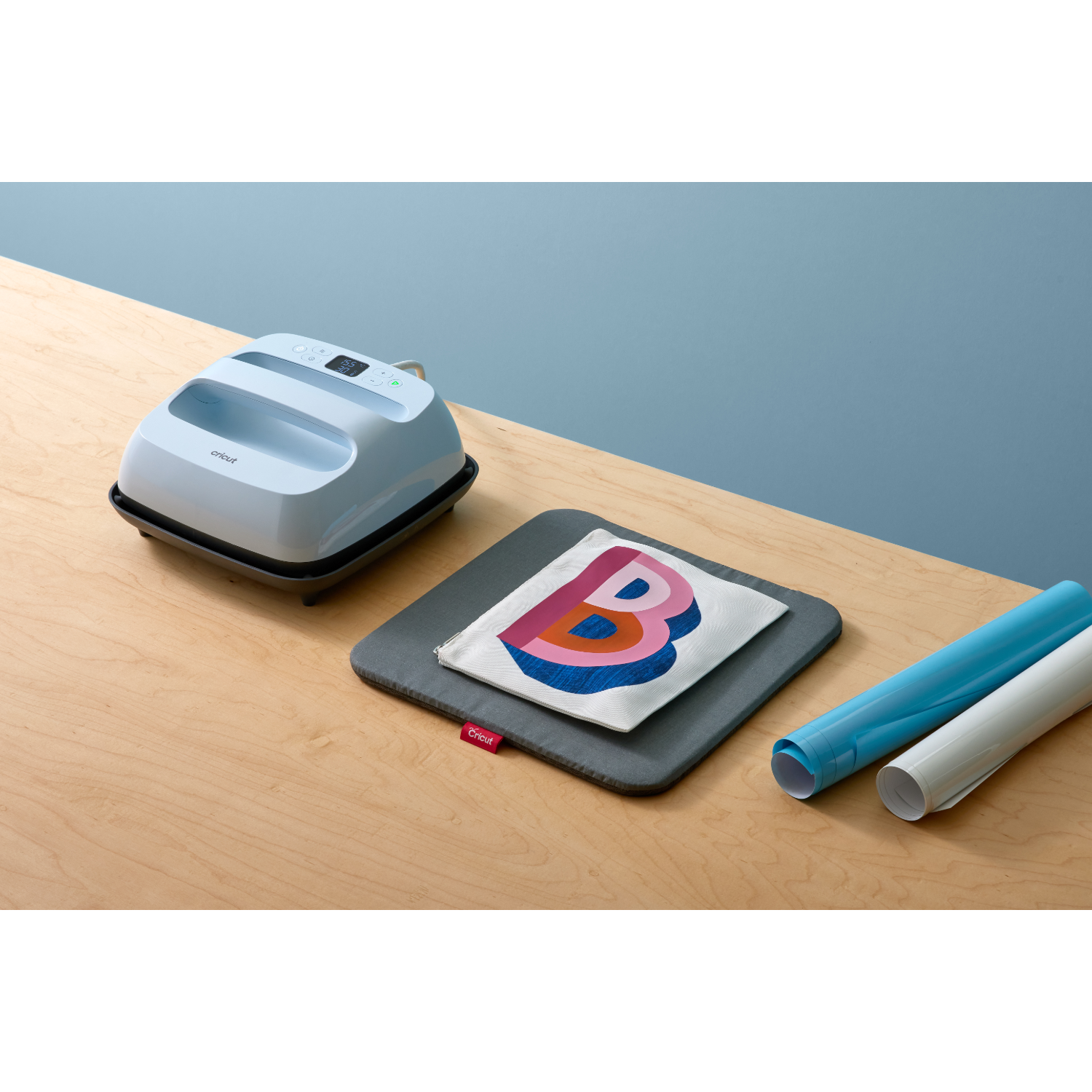 Heat press machine with a printed design, blue and white vinyl rolls.
