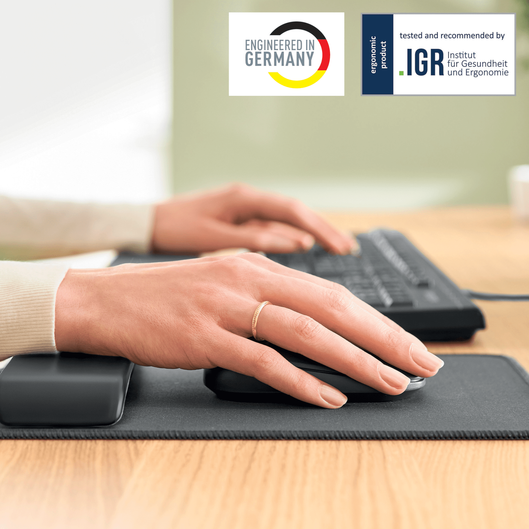 Kezek egeret és billentyűzetet használnak az asztalon. "Engineered in Germany" és "IGR" logók.