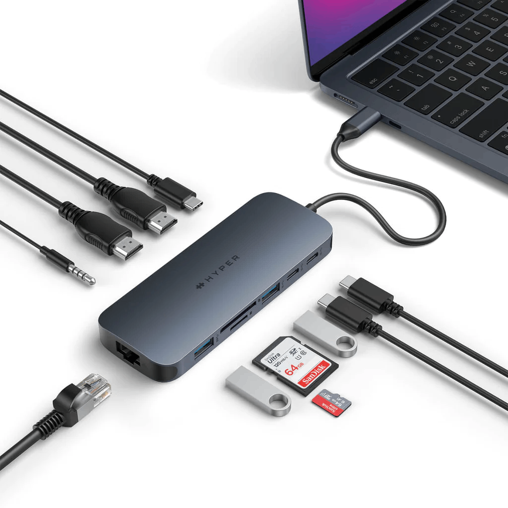 Ordenador portátil con concentrador USB-C conectado y varios accesorios: cables, tarjetas SD y conectores.