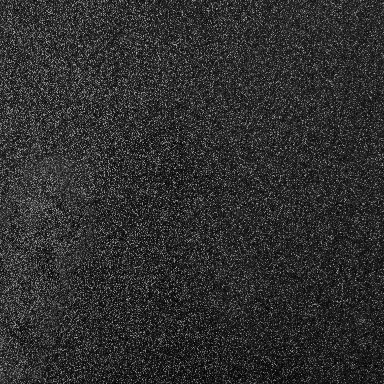Close-up of a rough, black surface with a textured pattern, suggesting a grainy or stone-like material.
