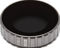 Kreisförmiger Objektivfilter mit Markierungen und dunklem Inneren. Metallisch silberne Farbe und geriffelte Kanten.