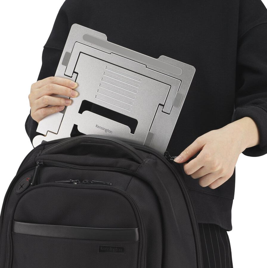 Egy személy egy ezüst laptopállványt tesz egy fekete hátizsákba.