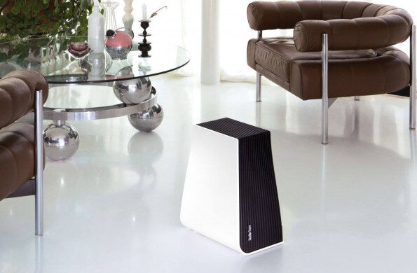 Biało-czysty oczyszczacz powietrza w nowoczesnym salonie ze szklanym stołem i białą podłogą.