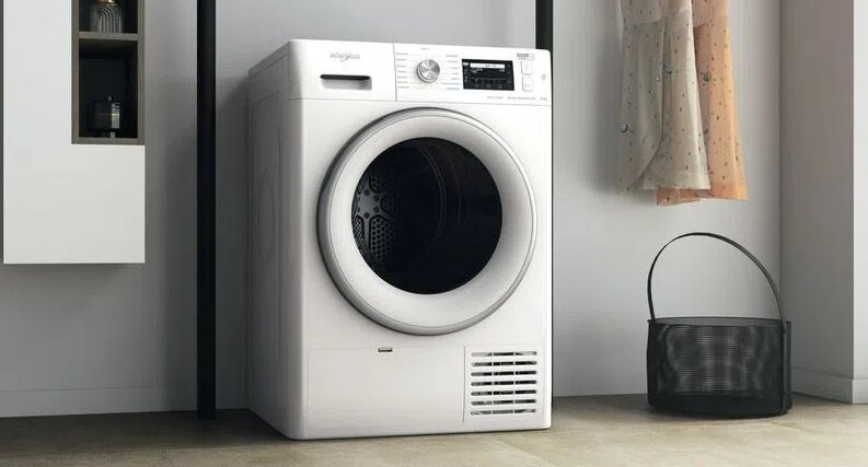 Biała suszarka z czarnym koszem i wiszącymi w tle sukienkami.