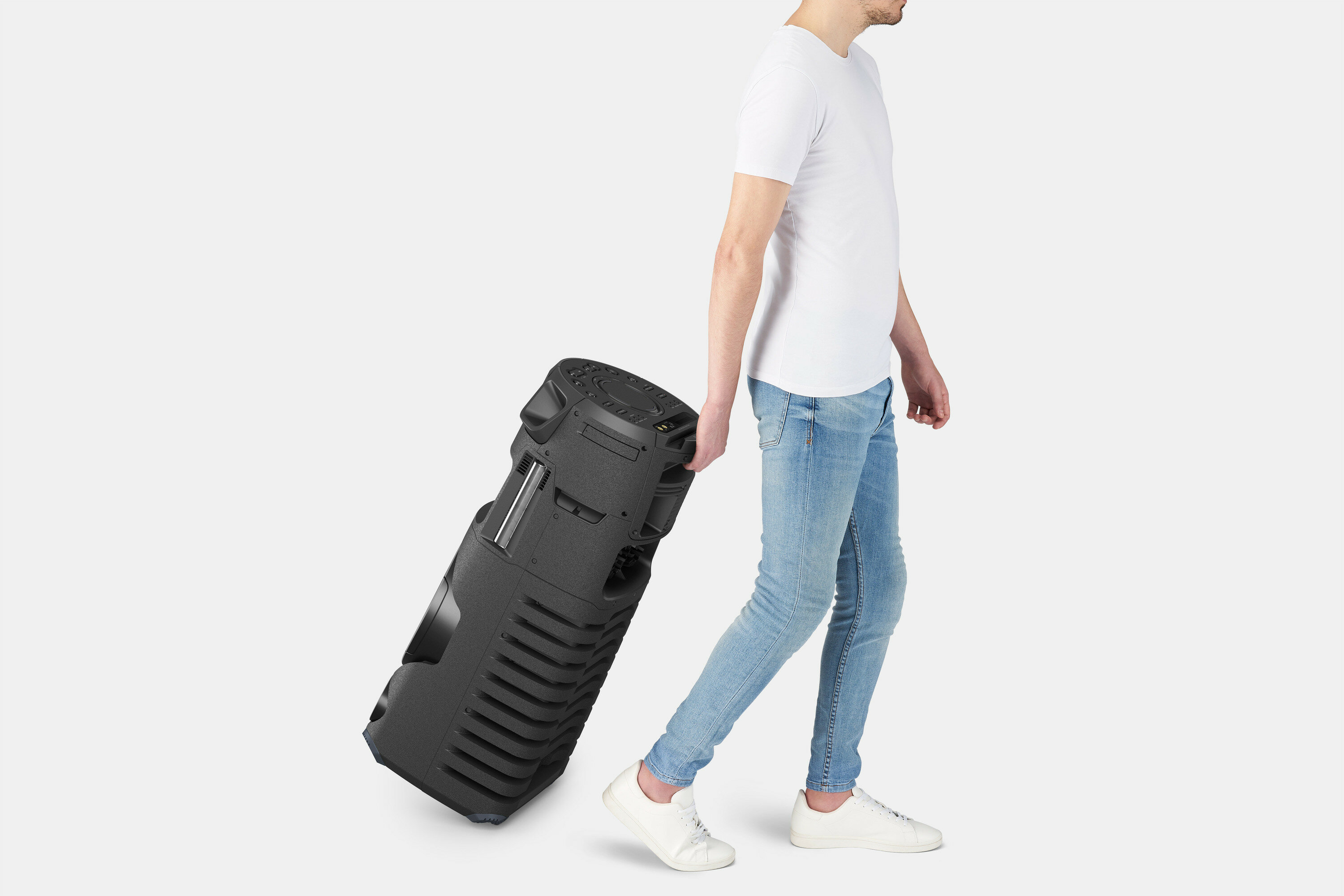 Mężczyzna ciągnie duży czarny głośnik na kółkach.