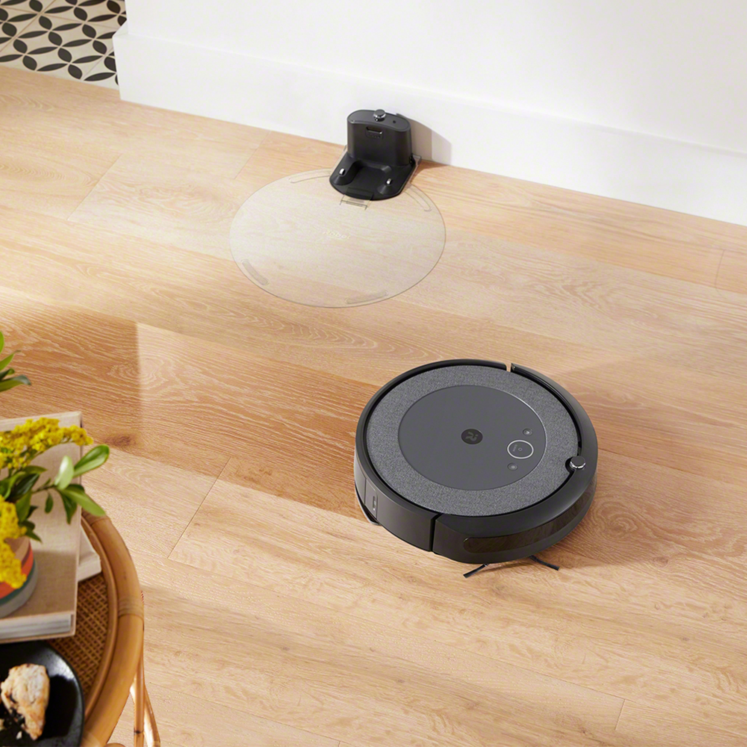 Robotstofzuiger op houten vloer, laadstation op achtergrond.