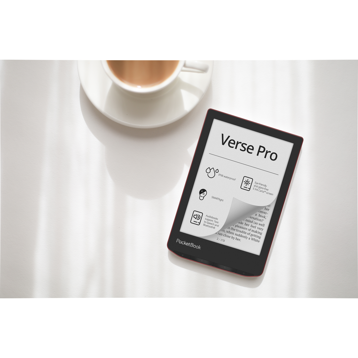 E-reader on a table with a cup of tea. Screen shows text, red border.