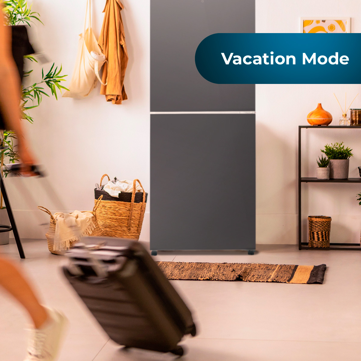 Un refrigerador gris en una habitación. Tiene una etiqueta de 'Modo Vacaciones' y una persona caminando.