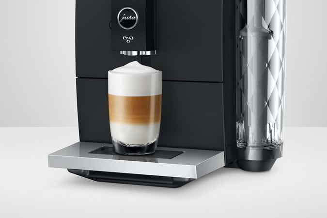 Cafetera Jura ENA 8 negra. Sirve un latte macchiato en un vaso.
