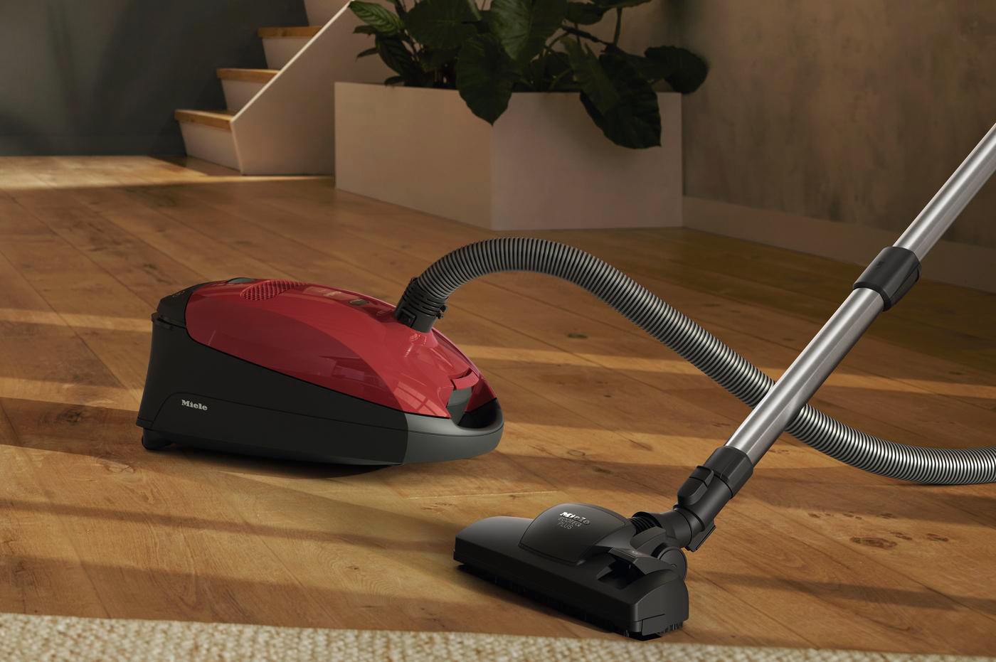 Roter und schwarzer Staubsauger auf Holzboden mit Teppich, Düse befestigt.