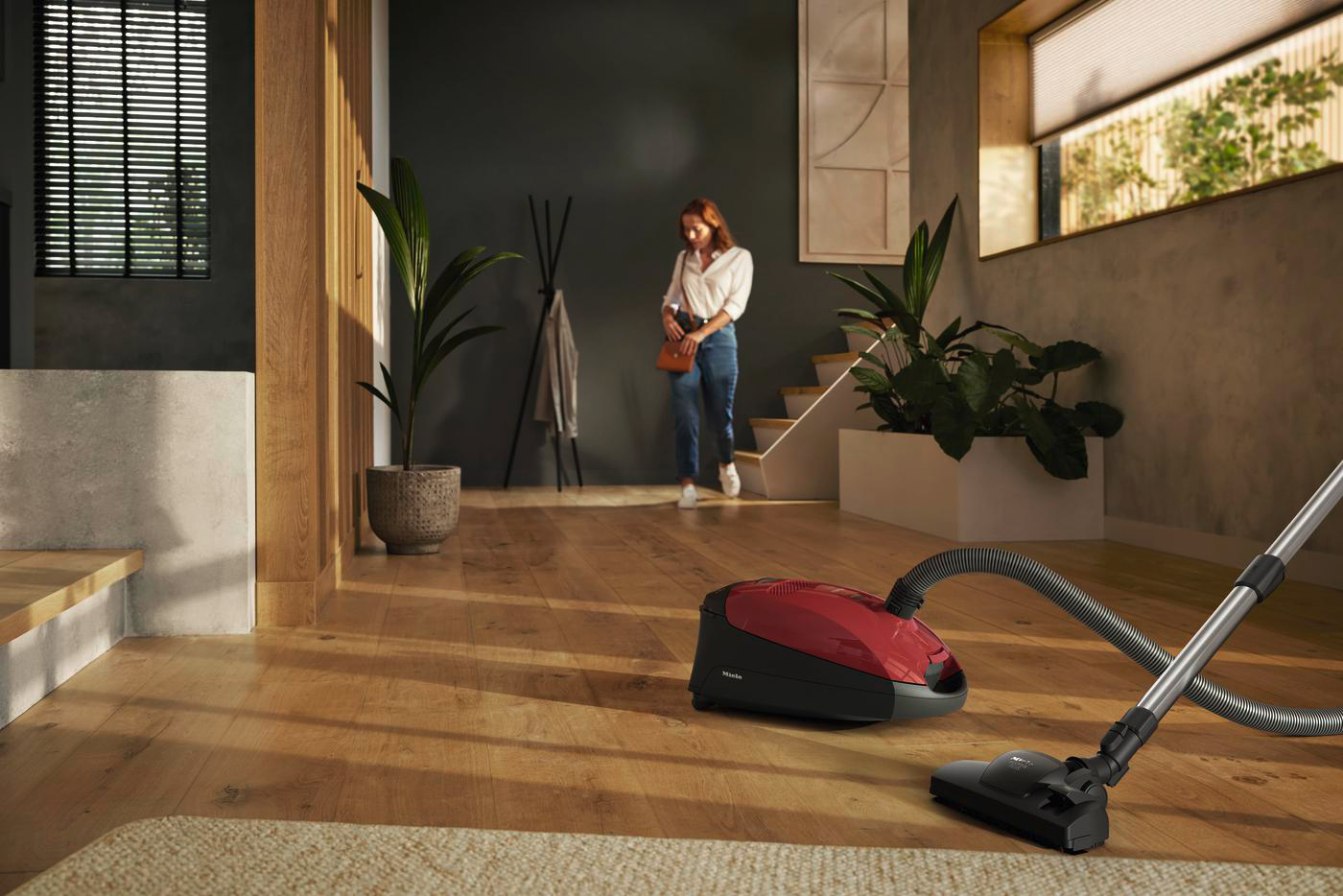 Frau und Staubsauger in einem Raum mit Holzboden.