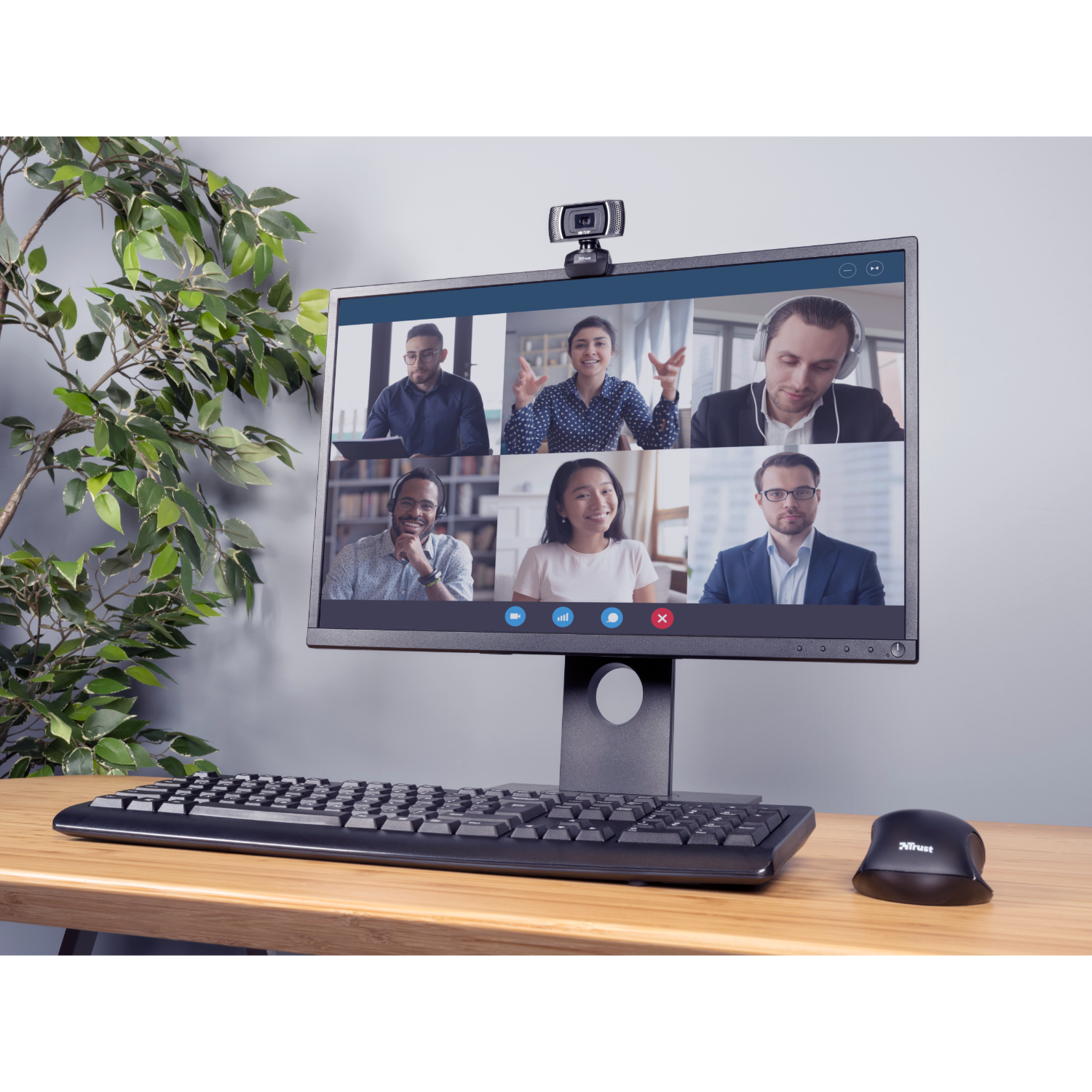 Desktopcomputer met webcam die een videogesprek toont. Toetsenbord, muis en plant zijn ook zichtbaar.