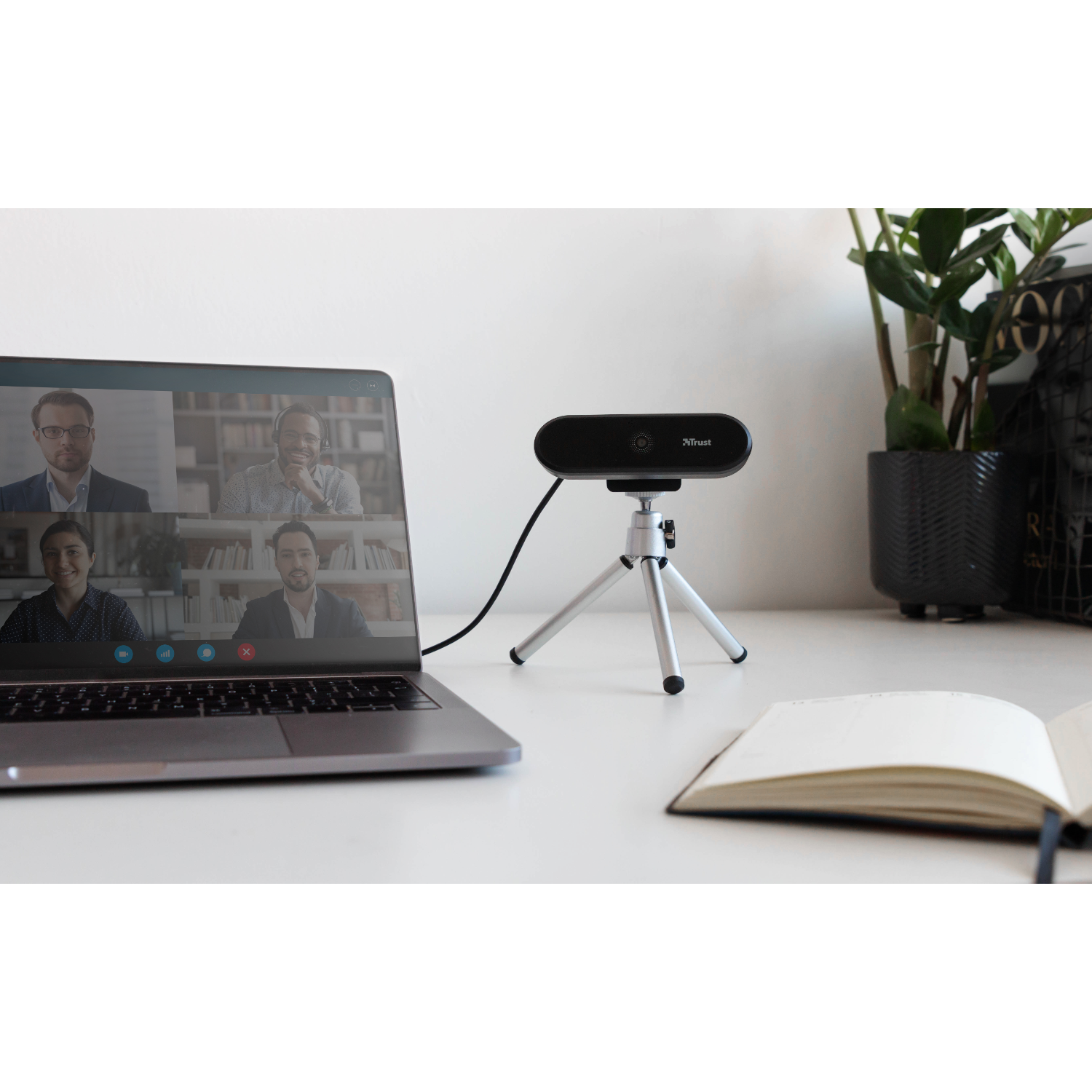 Laptop displaying a video call with four people, and a webcam on a tripod.