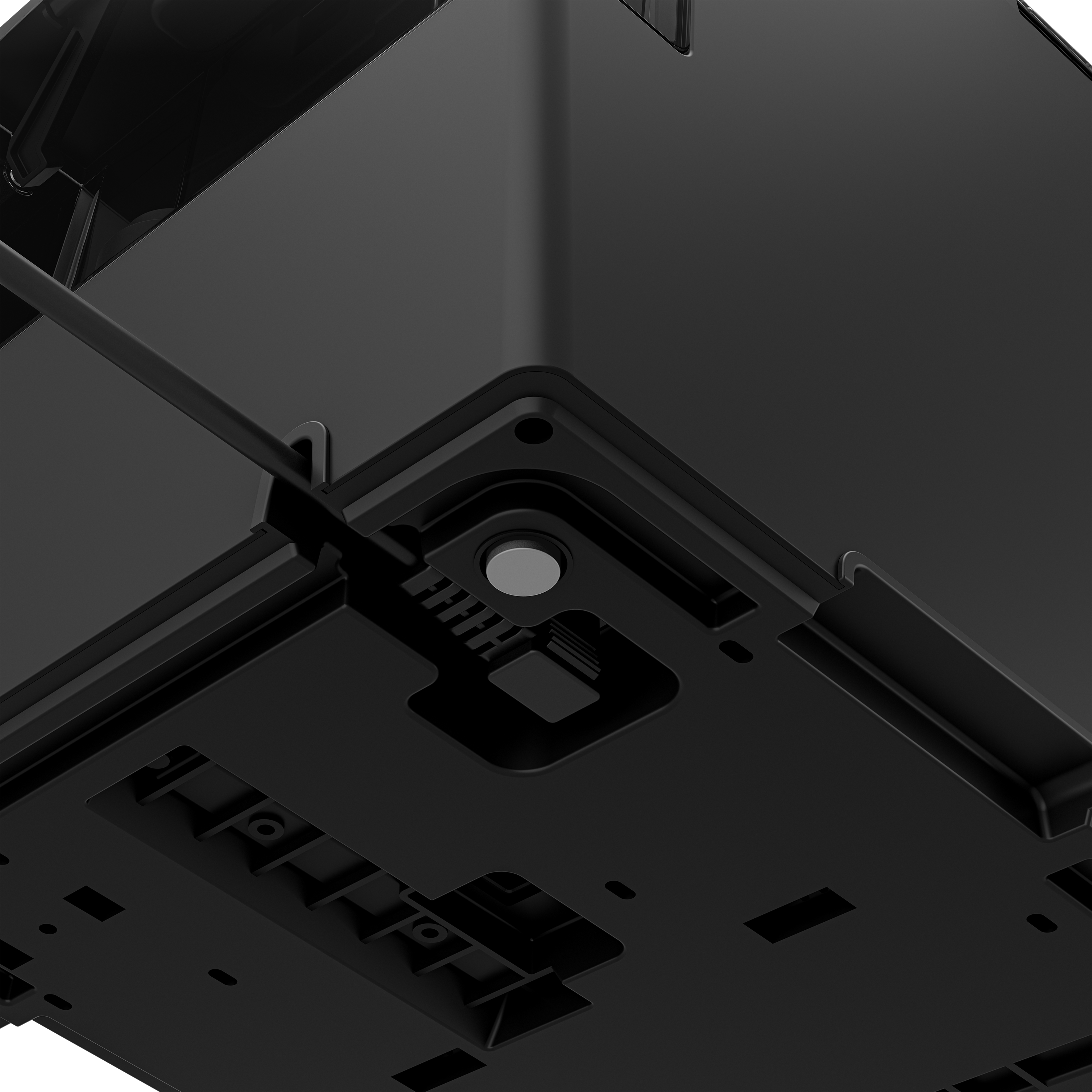 Yakın çekim, siyah bir cihazın altı, destek ayakları ve küçük, gri bir mıknatıs ile.