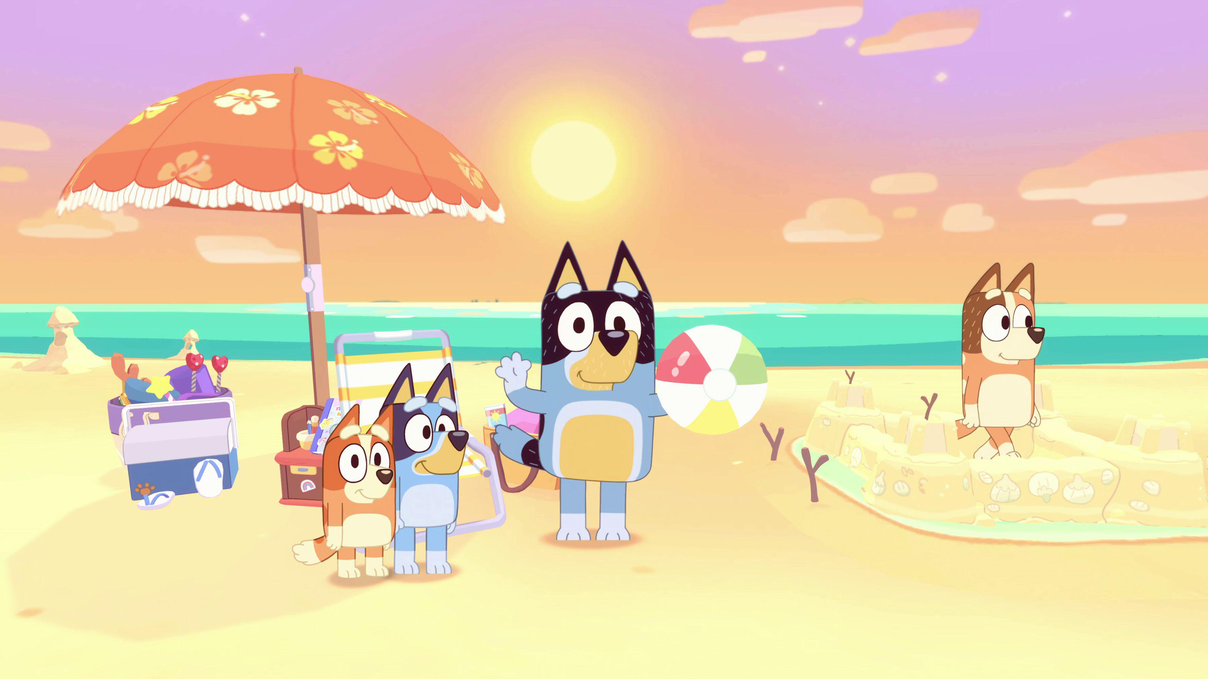 Vier Zeichentrickhunde an einem Strand mit Sonnenschirm und Sandburg, die Sonne ist im Hintergrund.