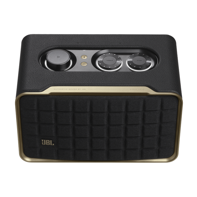 Un altavoz negro con adornos y controles dorados. El frente tiene una rejilla de altavoz.