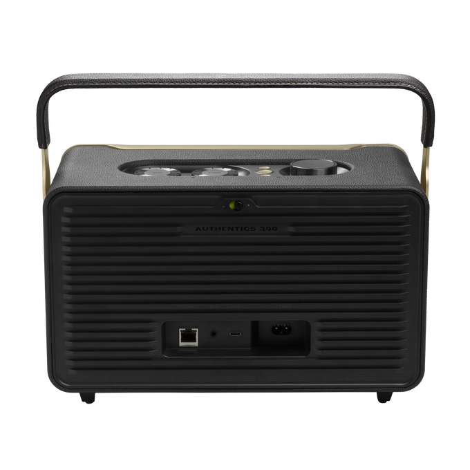 Altavoz negro con asa y detalles dorados. Tiene un panel con puertos y botones en la parte trasera.