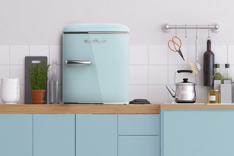 Refrigerador retro azul pastel con utensilios de cocina en mostrador madera.