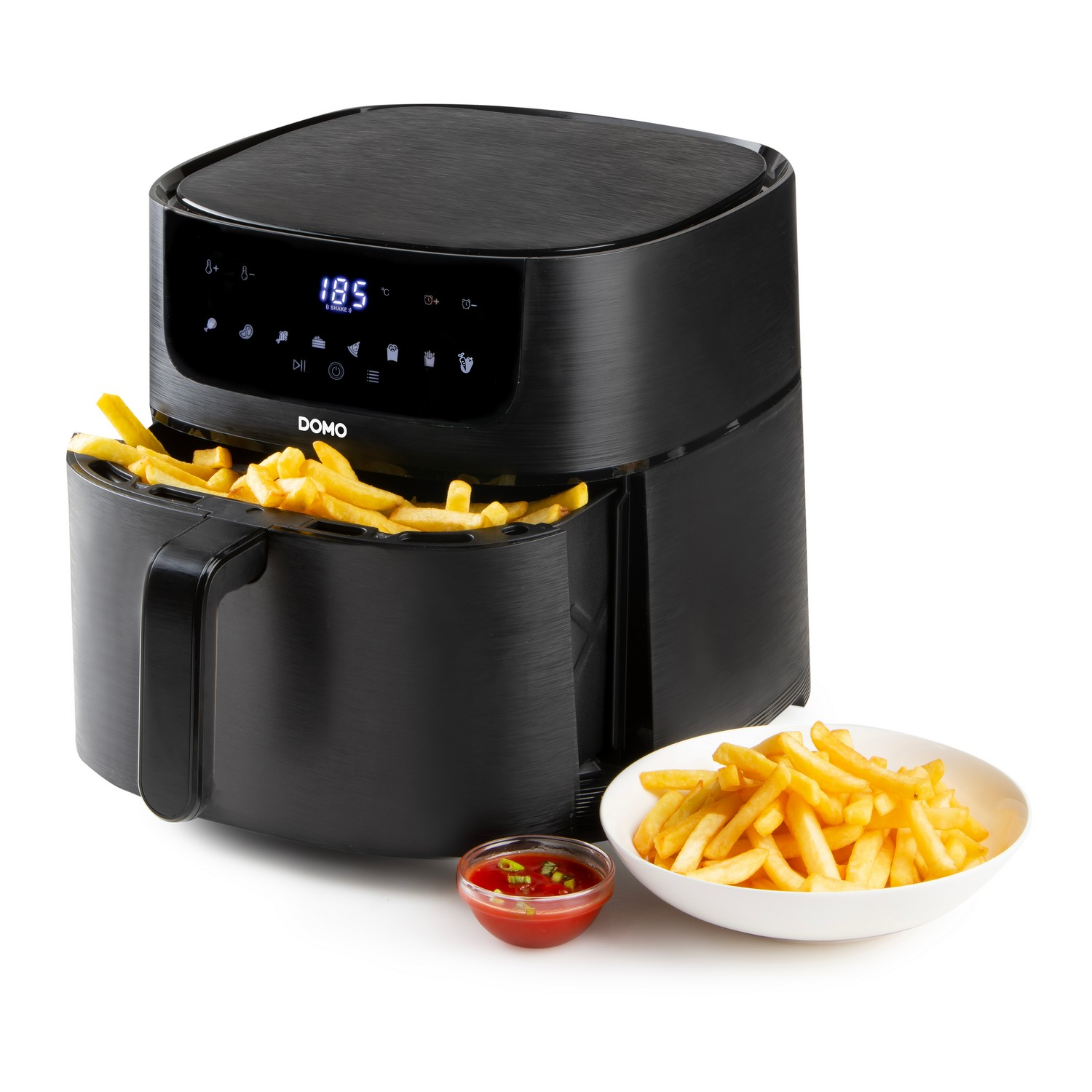 Friteuse à air noire avec frites à l'intérieur, un bol de frites et du ketchup à côté.