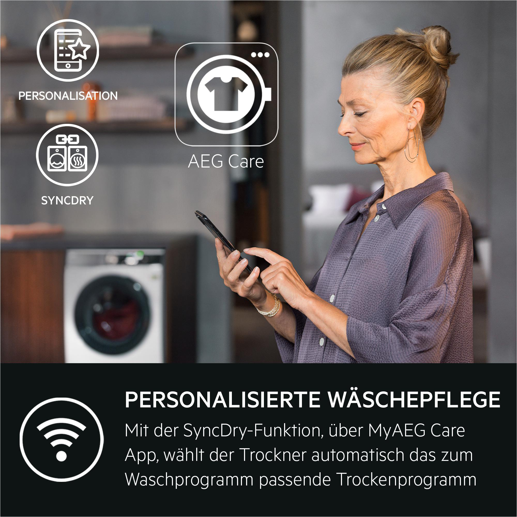 Frau hält ein Telefon, mit Text und Symbolen über eine Waschmaschine und ihre Funktionen, mit einer Waschmaschine.