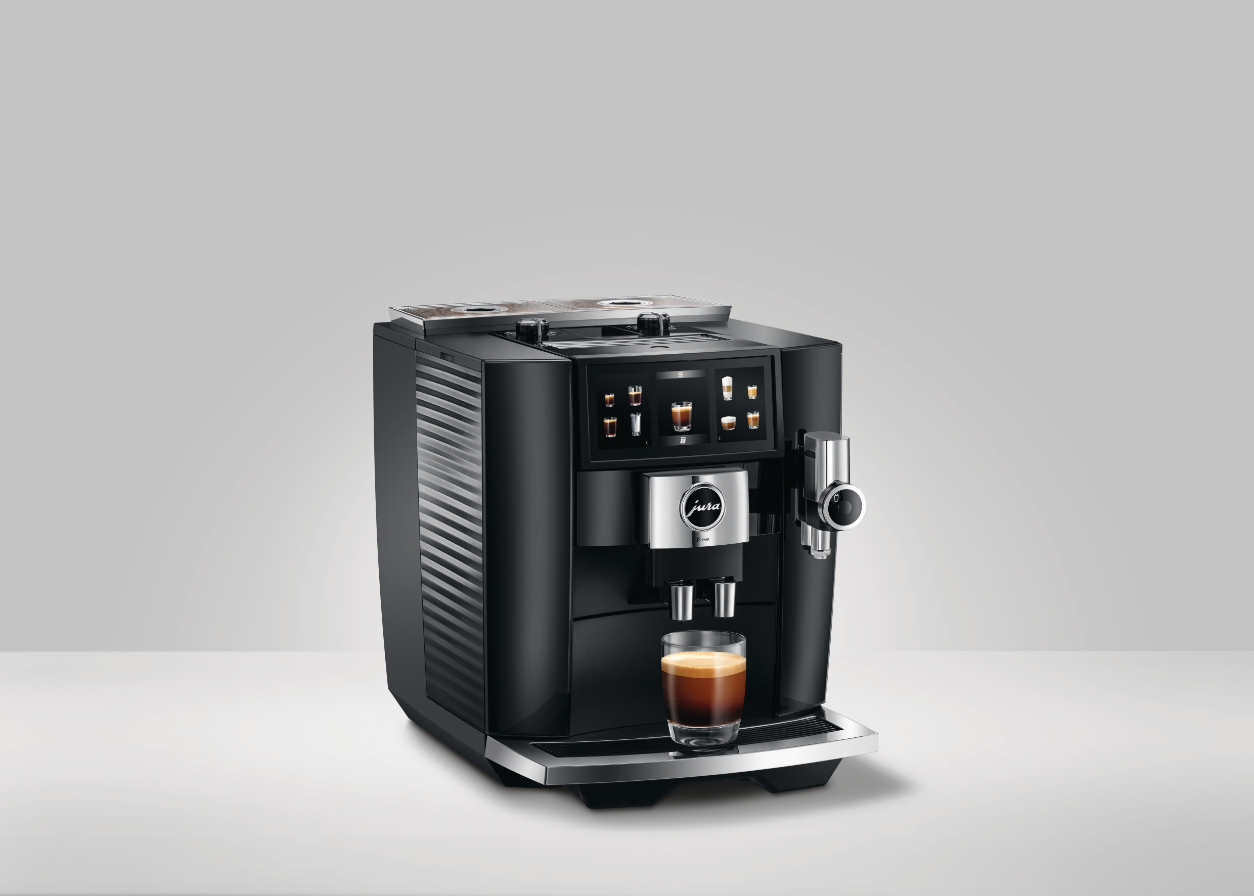 Schwarze Kaffeemaschine mit einem Glas Kaffee. Bildschirm mit Symbolen und Text: Jura.