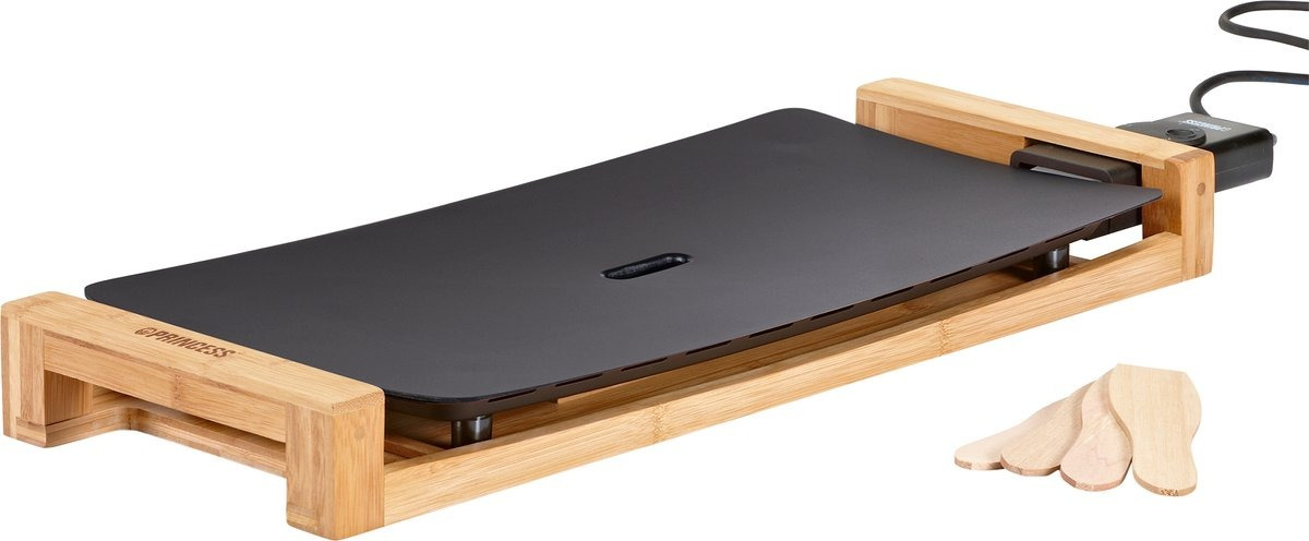 A black griddle on a bamboo frame with wooden spatulas. Princess brand is visible.